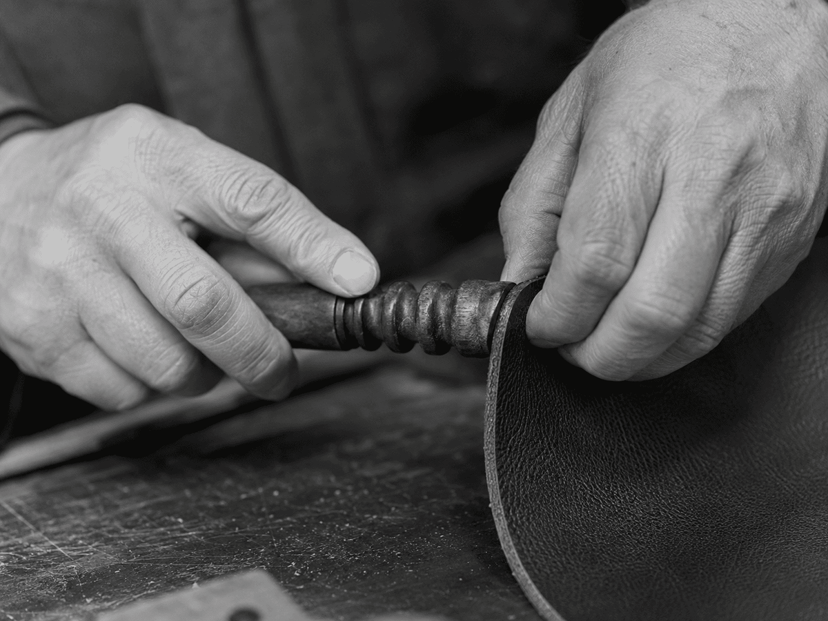 Leather artisan finishing an edge by hand