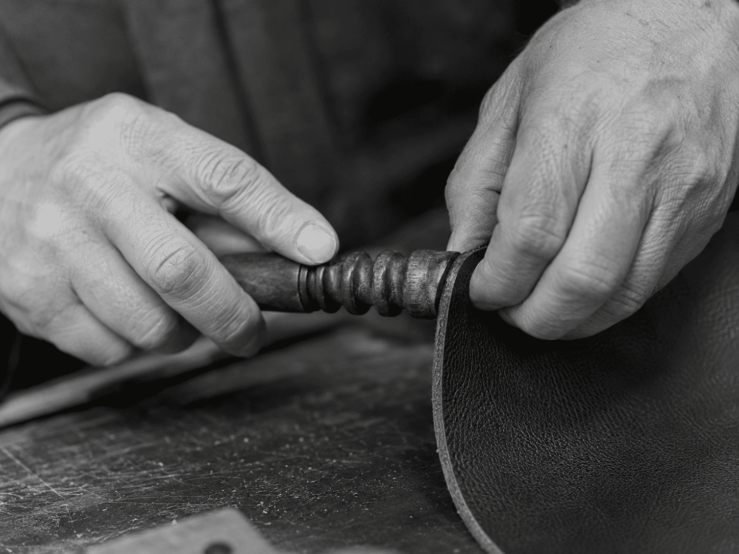 Lederhandwerker, der eine Kante von Hand bearbeitet